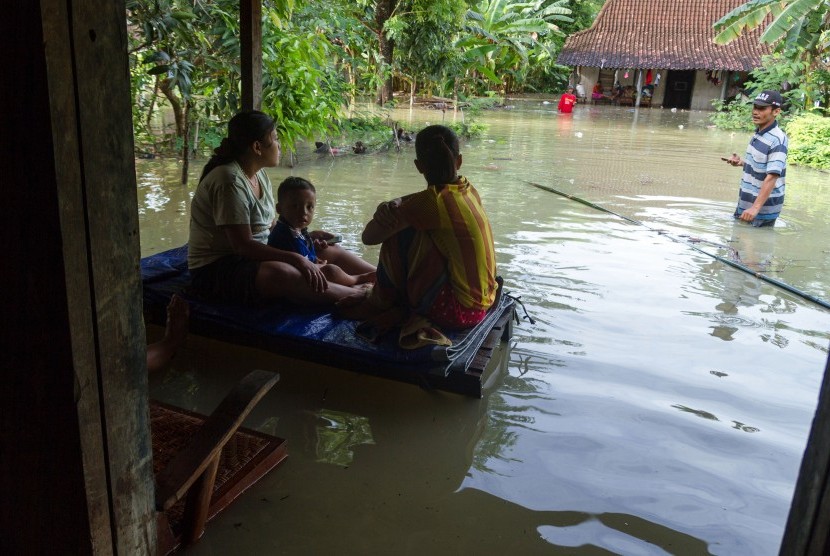 Warga bertahan di depan rumah mereka yang tergenang banjir (Ilustrasi) 
