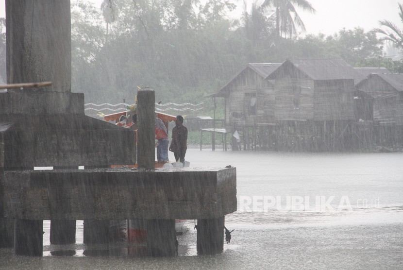 Warga berteduh di bawah Jembatan Banua Anyar saat hujan turun di Banjarmasin, Kalimantan Selatan, Senin (23/9/2019). 
