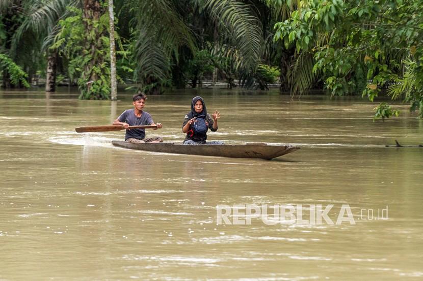 Warga berusaha keluar dari kepungan banjir menggunakan perahu di Desa Hagu, Kecamatan Matang Kuli, Aceh Utara, Aceh.