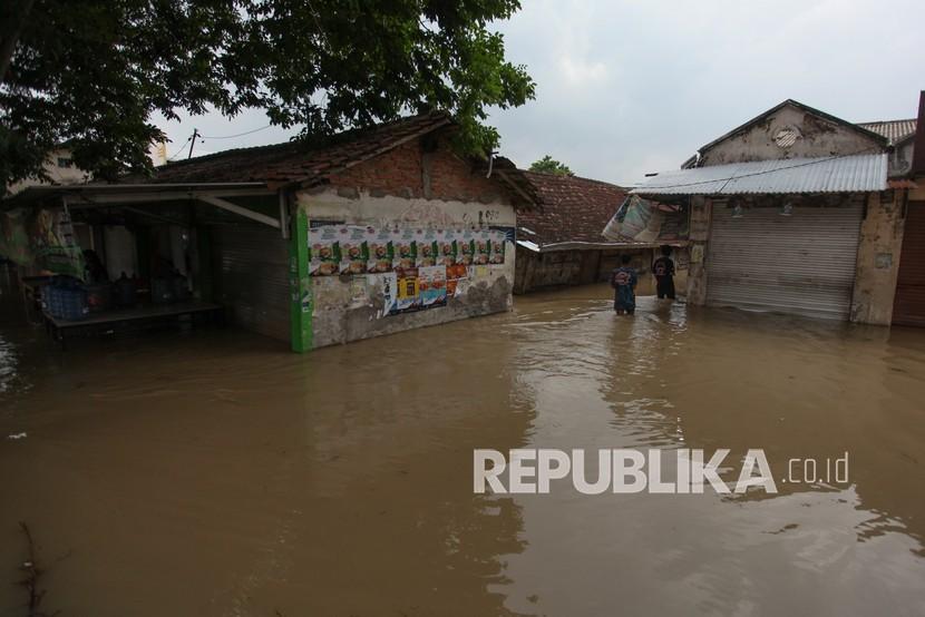 Warga berusaha menerobos banjir di Pasar Benjeng, Gresik, Jawa Timur, Jumat (5/11/2021). Banjir tersebut disebabkan meluapnya air Kali Lamong yang mengakibatkan sejumlah desa di Kecamatan Balongpanggang dan Kecamatan Benjeng terendam banjir. 