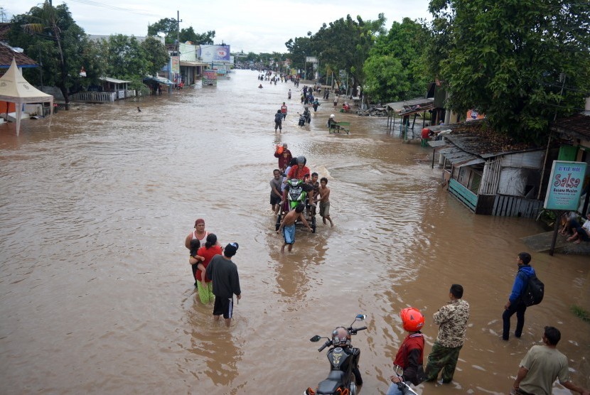 Warga berusaha menerobos banjir yang menggenangi Jalan Pantura Kraton, Pasuruan, Jawa Timur, Kamis (30/6).(Antara/Umarul Faruq)  