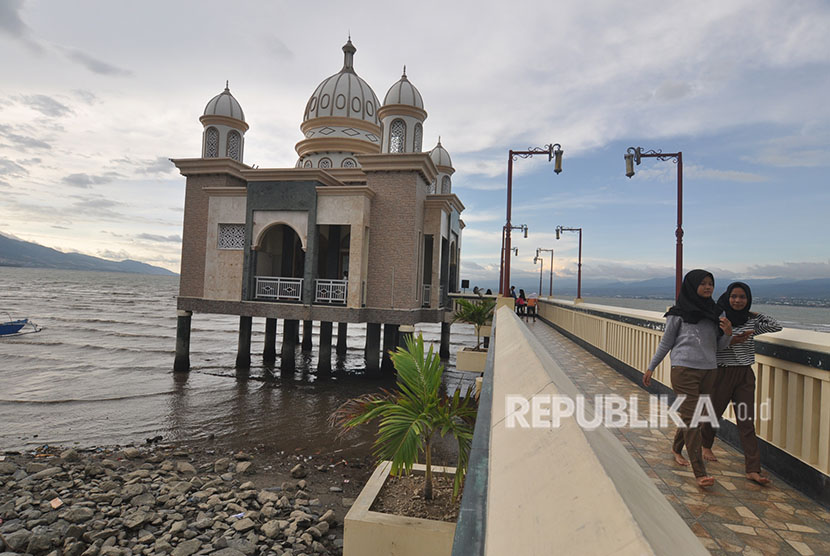 Warga berwisata sambil menunggu datangnya waktu berbuka di Masjid Terapung Arkam Babu Rahman di Pantai Teluk Palu, Sulawesi Tengah, Sabtu (19/5).