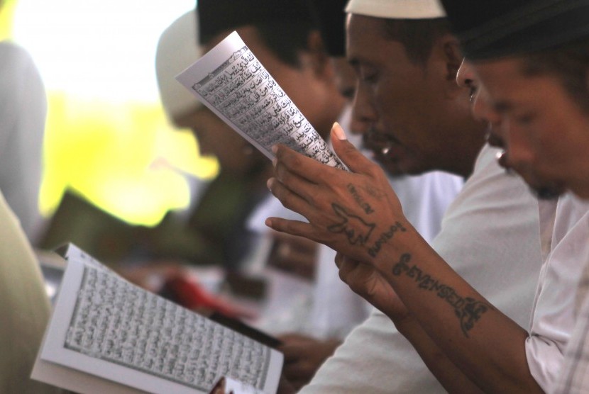 Warga binaan membaca Alquran saat mengikuti kegiatan Khatam Alquran massal di Lapas kelas IIB Indramayu, Jawa barat, Kamis (20/4).