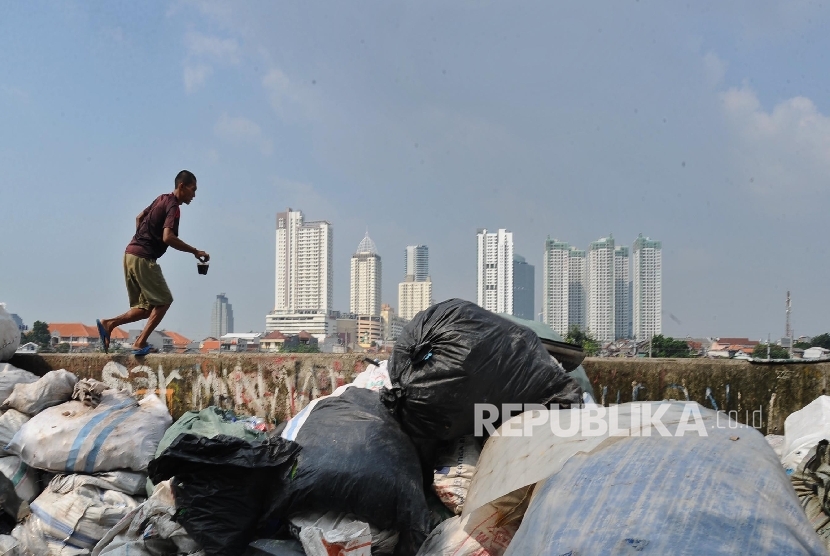 Warga brerjalan saat mengumpulkan sisa produk plastik di Jakarta, Senin (18/7)