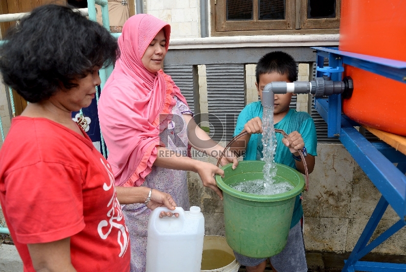 Warga dan anak-anak mengisi air bersih ke dalam jerigen dan ember saat mendapatkan bantuan air bersih di wilayah Kampung Melayu Besar, Tebet, Jakarta Selatan, Ahad (8/11).  (Republika/Prayogi)