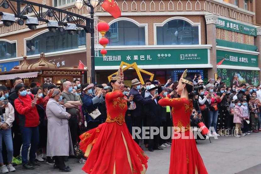 Warga dan pengunjung di International Grand Bazaar, Urumqi, Ibu Kota Daerah Otonomi Xinjiang, China, Kamis (22/4/2021), menyaksikan tari-tarian tradisional masyarakat etnis minoritas Muslim Uighur. Grand Bazaar merupakan pusat keramaian terbesar di Urumqi dan menjadi salah satu tujuan wisata utama Xinjiang. 