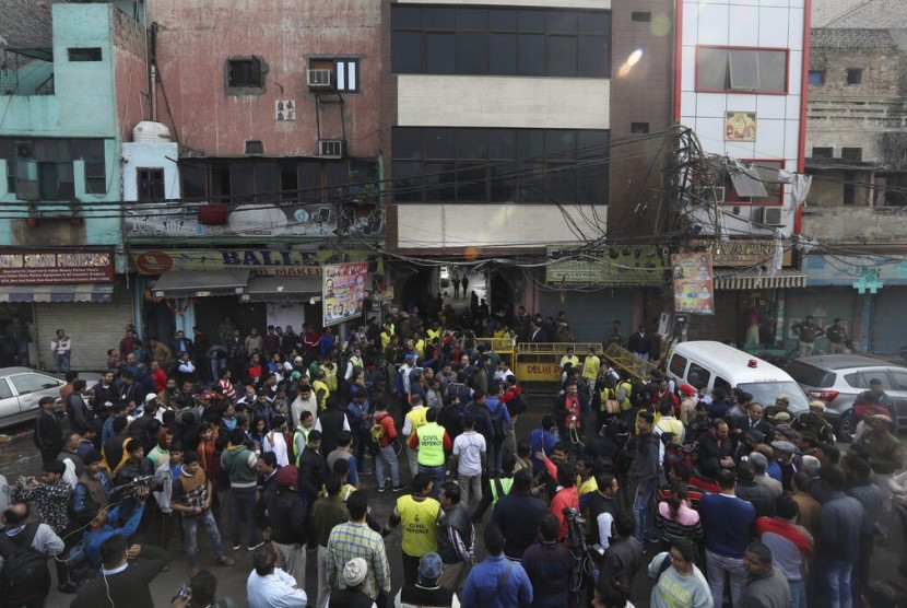 Warga dan petugas berkumpul di luar pasar yang terbakar di New Delhi, India, Ahad (8/12). Sekitar 43 orang meninggal dunia akibat kebakaran tersebut.