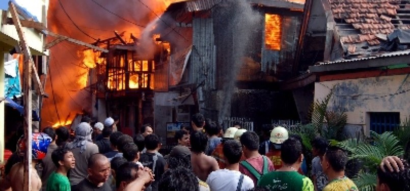 Warga dan petugas pemadam kebakaran berusaha memadamkan api yang membakar permukiman warga di kawasan Jalan Lautze, Jakarta Pusat, Selasa (7/6). 