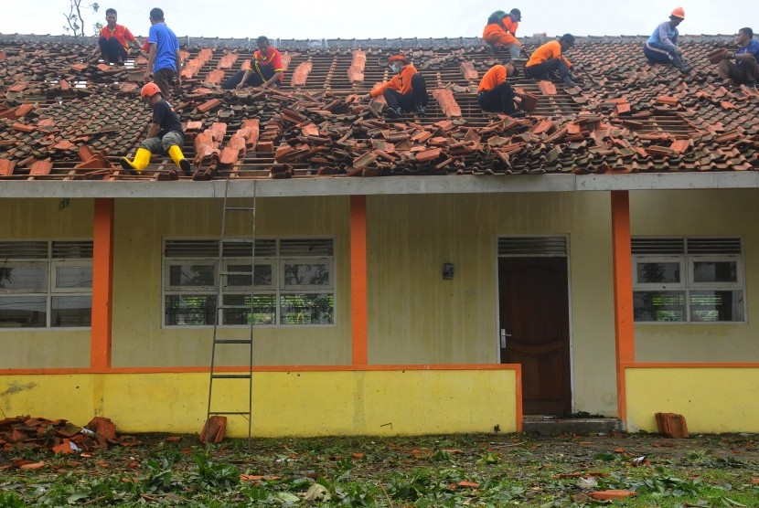 Warga dan relawan bergotong royong memperbaiki atap sekolah SMK Muhamadiyah yang rusak pascabencana angin puting beliung di Sidorejo Lor, Salatiga, Jawa Tengah, Jumat (9/12).