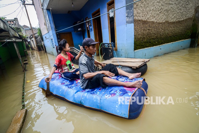 Warga dengan menggunakan perahu karet melintasi banjir di Kampung Bojong Asih, Desa Dayeuhkolot, Kabupaten Bandung, Jawa Barat, Selasa (6/3).