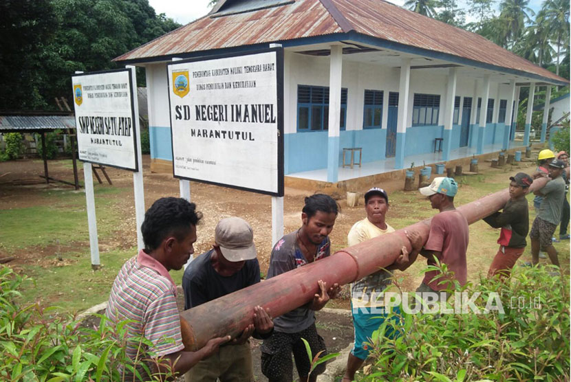 Warga desa di Maluku bergotong royong menyiapkan tiang listrik di desa mereka. 