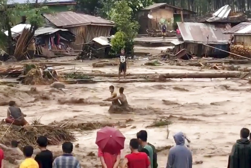 Warga desa mencoba menyeberang banjir di Lanao del Norte, Zamboanga Pennisula, di bagian selatan Filipina, Jumat (22/12). Banjir menjerang kawasan itu akibat badai tropis. Badai tersebut terpantau melemah dalam perjalanannya menuju Vietnam, Selasa (26/12).