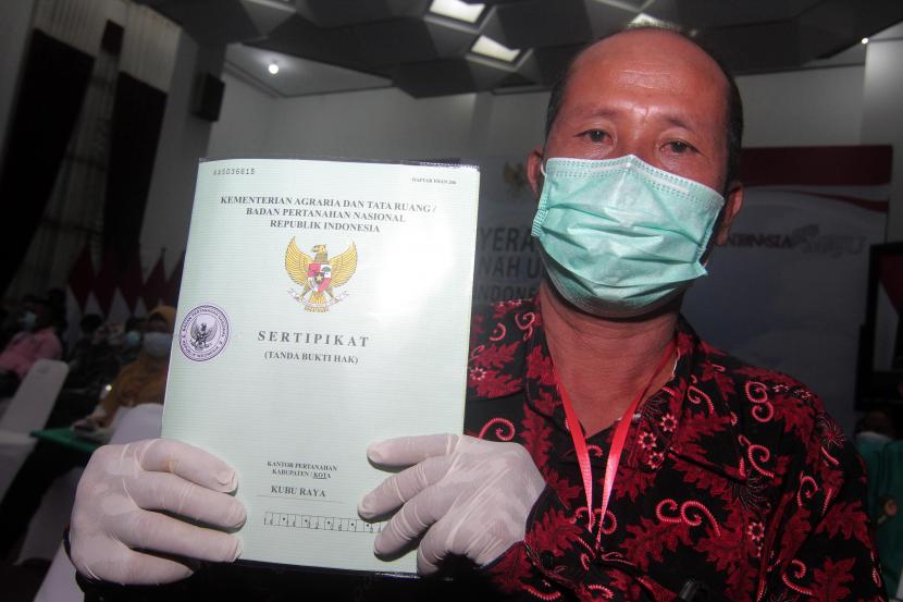 Warga memperlihatkan sertifikat tanah yang diterima usai acara penyerahan dari Presiden Joko Widodo secara virtual  (ilustrasi)