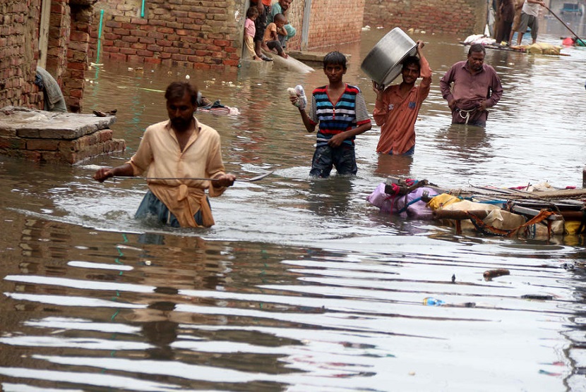 Warga di Hyderabad Pakistan berjalan melewati banjir akibat hujan deras. Hujan deras Monsun hingga kini telah merenggut 300 nyawa di Hyderabad, Pakistan