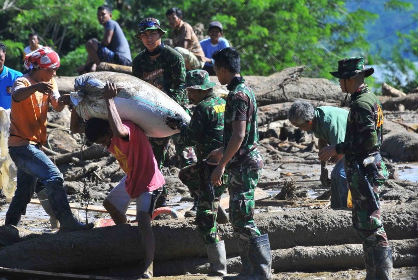 Warga dibantu TNI membawa barangnya setelah bencana banjir bandang di Desa Sintuwu, Palolo, Sigi, Sulawesi Tengah, Rabu (18/5). (Antara/Muhammad Adimaja)