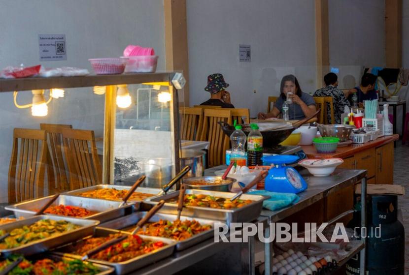 Warga duduk dan makan di restoran dengan tempat duduk yang dipartisi dengan lembaran plastik tembus pandang di Bangkok, Thailand, Selasa (5/5). Restoran yang digenangi banjir di Thailand justru menyedot pengunjung untuk datang. Ilustrasi. 