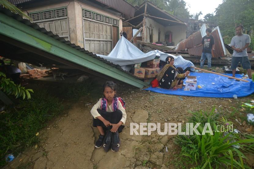 Warga duduk di halaman rumahnya yang rusak akibat gempa di Jorong Pinagar, Nagari Aua Kuning, Kabupaten Pasaman Barat, Sumatera Barat, Jumat (25/2/2022). Badan Nasional Penanggulangan Bencana (BNPB) menyatakan gempa berkekuatan magnitudo 6,2 di Pasaman Barat dan sekitarnya itu mengakibatkan tujuh warga meninggal dunia. 