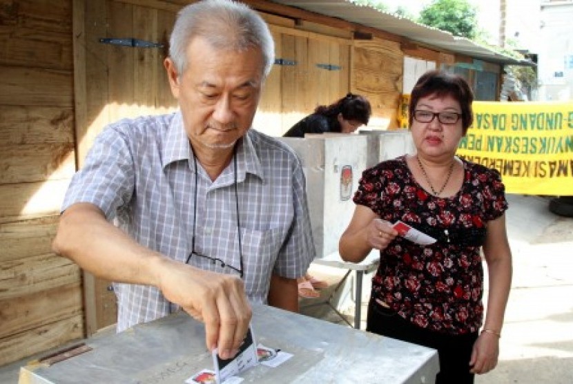 Warga etnis Tionghoa memasukkan kertas surat suara kedalam kota suara saat menggunakan hak pilihnya pada pemungutan suara Pemilu Presiden/wakil Presiden 2014 