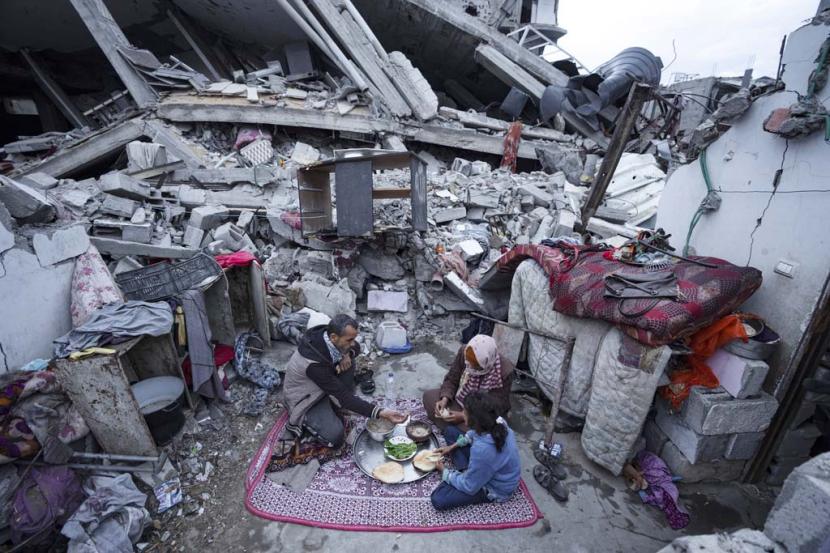 Warga Gaza berbuka puasa selama bulan suci Ramadhan di luar rumah mereka yang hancur akibat serangan udara Israel di Rafah, Jalur Gaza.