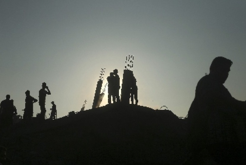 Warga Gaza berdiri di atas reruntuhan bangunan yang hancur dibom pesawat udara Israel.