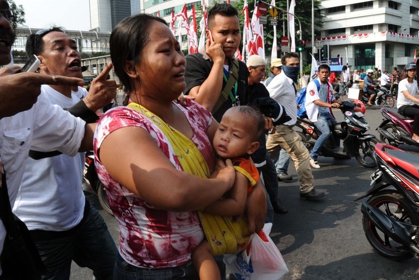 Warga ibu-ibu mengendong anak sambil menanggis saat bentrokan terjadi di Jl Thamrin, Jakarta, Kamis (21/8). Massa pendukung Prabowo-Hatta sempat terjadi bentrokan dengan petugas keamanan, dan sempat ditembakkan gas air mata.