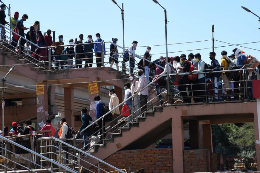 Warga India mengantre di sebuah terminal bus perbatasan Uttar Pradesh dekat New Delhi, India, Sabtu  (28/3). India menghadapi gelombang eksodus warga dari kota ke desa akibat lockdown.
