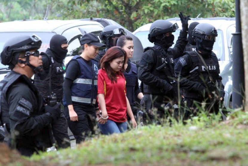 Warga Indonesia Siti Aisyah (berkaus merah) dengan dikawal polisi bersenapan otomatis saat akan masuk ke Pengadilan Sepang di Sepang, Malaysia, Rabu (1/3). Bersama perempuan Vietnam, ia diduga membunuh warga Korea Utara Kim Jong-nam.