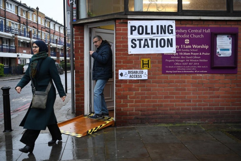 Warga Inggris di London bagian selatan keluar dari tempat pemungutan suara usai memberikan suaranya dalam Pemilu pada Kamis (12/12).