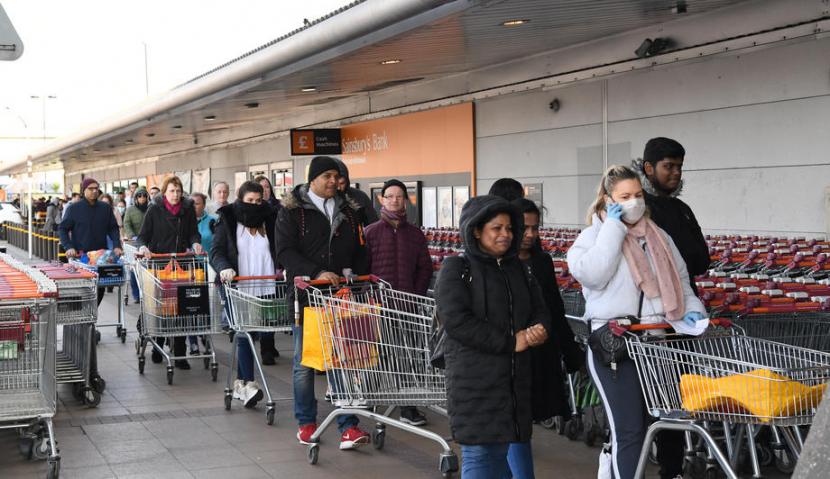 Warga Inggris mengantre di sebuah supermarket di London, Inggris, Ahad (22/3). Banyak orang Inggris kemungkinan besar tertular Covid-19 di supermarket.