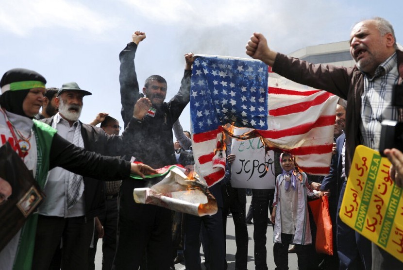 Warga Iran membakar bendera AS di Teheran, Iran. Sanksi AS merugikan Iran sehingga terjadi inflasi dan penurunan nilai mata uang Iran. Ilustrasi.