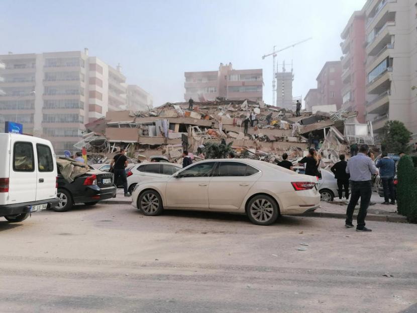 Warga  Izmir menghampiri gedung yang runtuh setelah gempa berkekuatan 7,0 yang berpusat di Laut Aegea, Turki, 30 Oktober 2020.