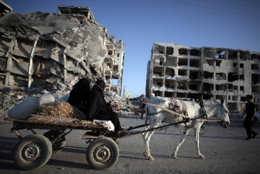Warga Jalur Gaza menaiki keledai diengan latar belakang gedung yang hancur dibombardir militer Israel.