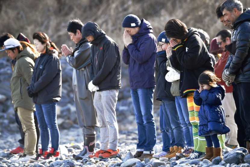 Warga Jepang mengenang korban tsunami tujuh tahun lalu di pinggir pantai Kesenuma di utara Jepang, Ahad (11/3).