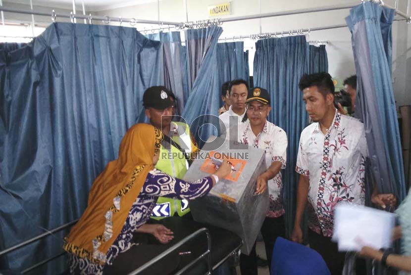 Warga Kabupaten Tasikmalaya yang sakit di RSUD Singaparna Medika Citrautama (SMC) melakukan pencoblosan dengan dibantu Panitia Pemungutan Suara (PPS) di TPS 09, Cikunten, Singaparna Kabupaten Tasikmalaya, Rabu (9/12). (Republika/Fuji EP) 