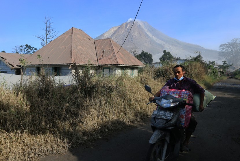 Warga kaki Gunung Sinabung mengevakuasi diri dengan mengendarai sepeda motor di Desa Gamber, Karo, Sumatra Utara, Ahad (22/5).