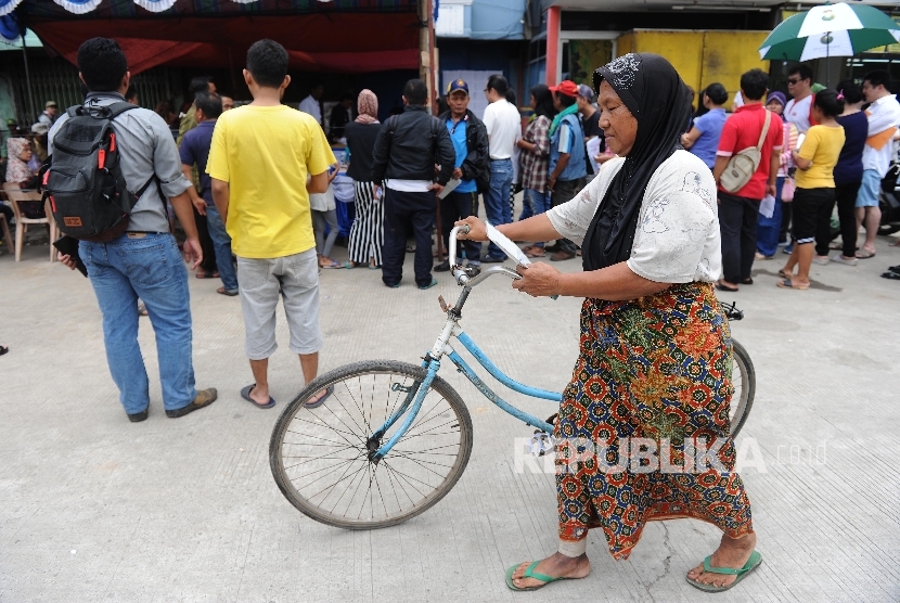 Warga Kampung Aquarium menuntun sepedanya usai mengikuti Pilkada DKI Jakarta di TPS 16, Penjaringan, Jakarta Utara, Rabu (15/2).