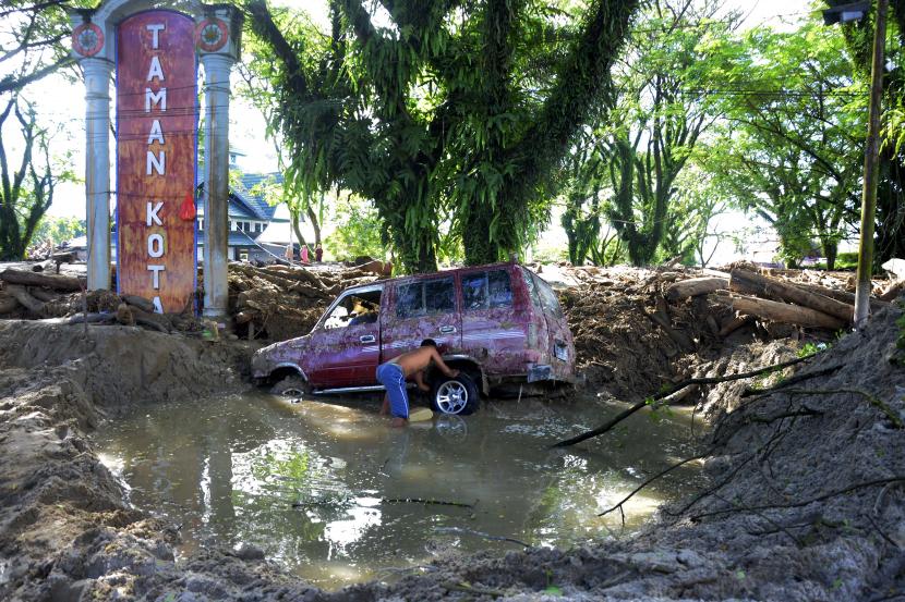 Warga korban banjir bandang melihat kondisi kendaraannya yang terseret material lumpur di kecamatan Masamba, Kabupaten Luwu Utara, Sulawesi Selatan, Jumat (17/7/2020). Hingga hari ini, jumlah korban meninggal mencapai 32 orang sementara puluhan lainnya masih dalam pencarian.