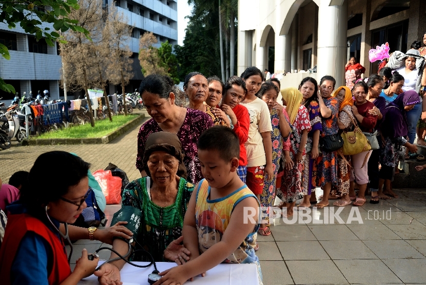 Warga korban banjir mengantri memeriksa kesehatan di lokasi pengungsian di Masjid Univesitas Borobudur, Jakarta,Rabu (22/2).
