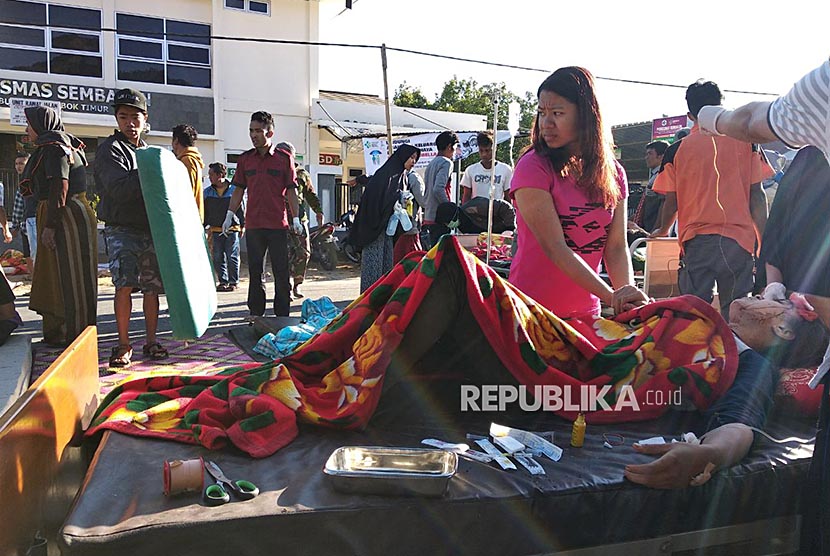 Warga korban gempa mendapatkan perawatan di luar Puskesmas Sembalun Selong, Lombok Timur, NTB, Minggu (29/7).