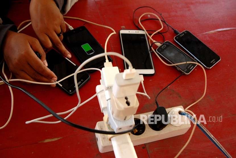 Warga korban gempa mengisi daya telepon genggamnya di halaman kantor Telkom, Palu, Sulawesi Tengah, Jumat (5/10). 