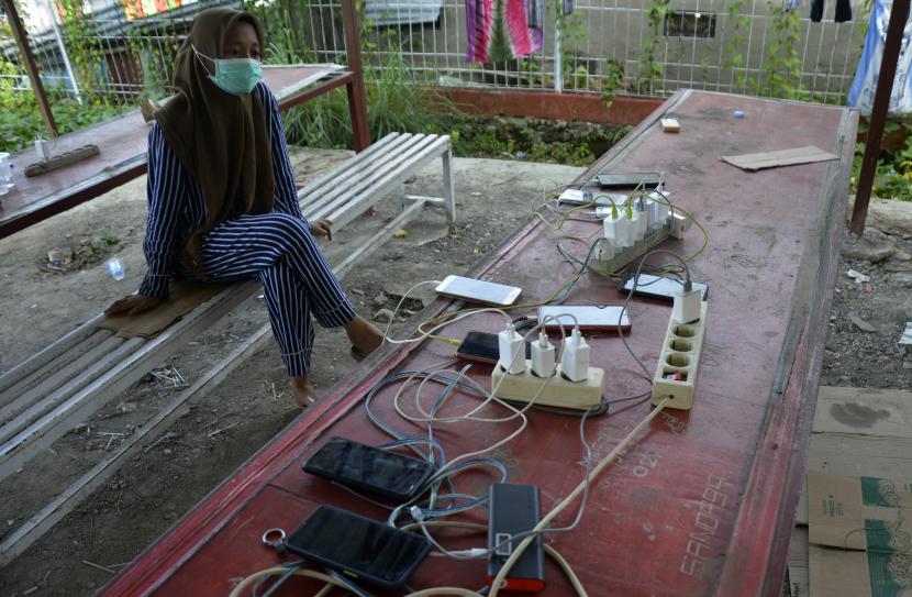 Warga korban gempa mengisi daya telepon genggamnya di halaman kantor Plaza Telkom, Kabupaten Mamuju, Sulawesi Barat, Senin (18/1/2021). Akibat sejumlah tempat pengungsian belum dialiri listrik, warga terpaksa mengisi daya telepon genggamnya di luar pengungsian agar dapat berkomunikasi dengan keluarganya