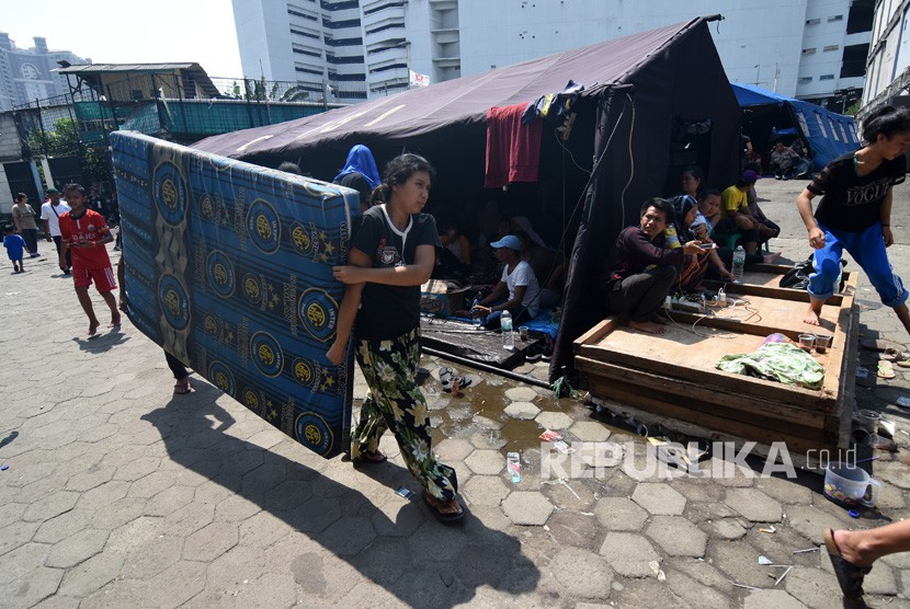 Warga korban kebakaran membawa kasur di posko pengungsian Kampung Bandan, Jakarta Utara, Ahad (12/5/2019).