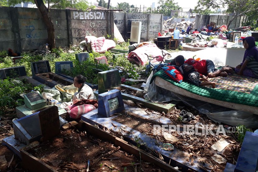 Warga korban penggusuran Kampung Palem Nuri, Kelurahan Panunggangan Barat, Kota Tangerang memilih bertahan dan tidur di atas pemakaman umum yang bersebelahan dengan lokasi penggusuran, Kamis (7/12).