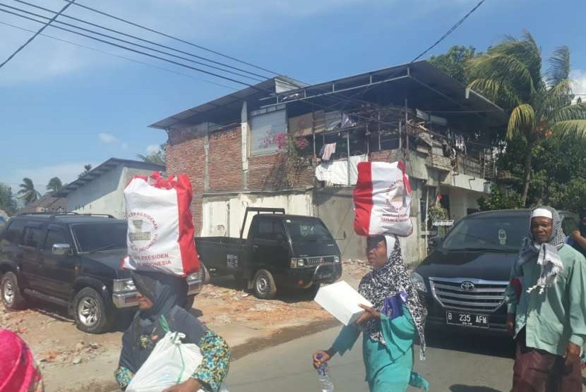 Warga korban terdampak gempa mengambil bantuan sembako dari Presiden Joko Widodo (Jokowi) di Pemenang, Kabupaten Lombok Utara, NTB, Ahad (2/9).