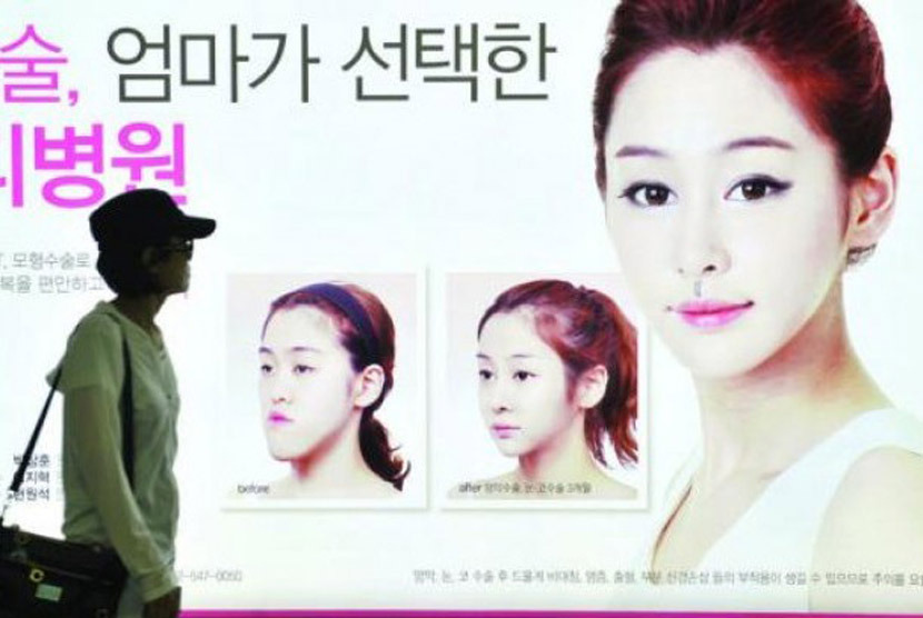 Warga Korea Selatan berjalan di depan sebuah iklan operasi Rahang Ganda. Jumlah penduduk Korea Selatan diperkirakan akan menurun sepertiganya pada sekitar tahun 2060 menjadi sekitar 35 juta orang. Saat ini total penduduk Korsel sebesar 51,3 juta dan tingkat kematian yang tinggi serta rendahnya tingkat fertilitas negara ini menjadi faktor penurunan tersebut.