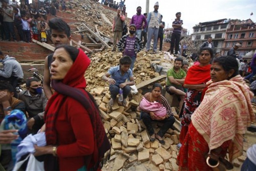  Warga kota Kathmandu duduk diatas reruntuhan bangunan yang hancur akibat gempa, Sabtu (25/4).