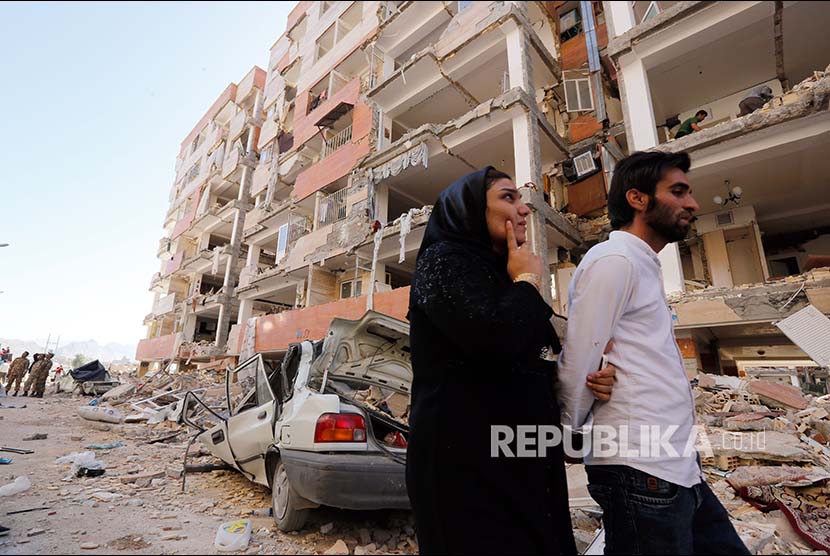 Warga Kota Sare Pole-Zahab propinsi Kermanshah melintasi reruntuhan bangunan yang rusak akibat gempa. Selasa (14/11).