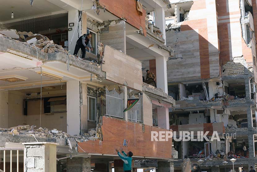 Warga Kota Sare Pole-Zahab propinsi Kermanshah mengumpulkan harta yang tersisa dari reruntuhan bangunan yang rusak akibat gempa. Selasa (14/11).