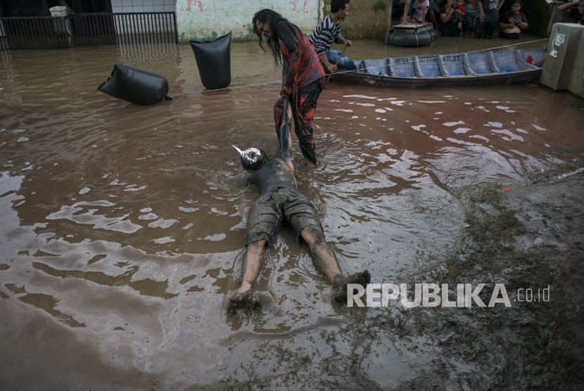 Warga melakukan aksi teatrikal di area banjir pada acara Pentas Bandung Lautan Banjir di Bojongasih, Dayeuhkolot, Kabupaten Bandung, Jawa Barat, Ahad (14//4/2019).