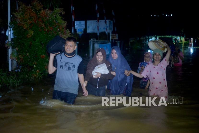 Warga melakukan evakuasi mandiri ke tempat yang lebih tinggi, akibat banjir merendam rumah mereka, di Lubuk Buaya, Padang, Sumatera Barat, Rabu (18/8/2021). Intensitas hujan tinggi sejak Rabu siang membuat air sungai meluap dan merendam pemukiman di kota itu. 